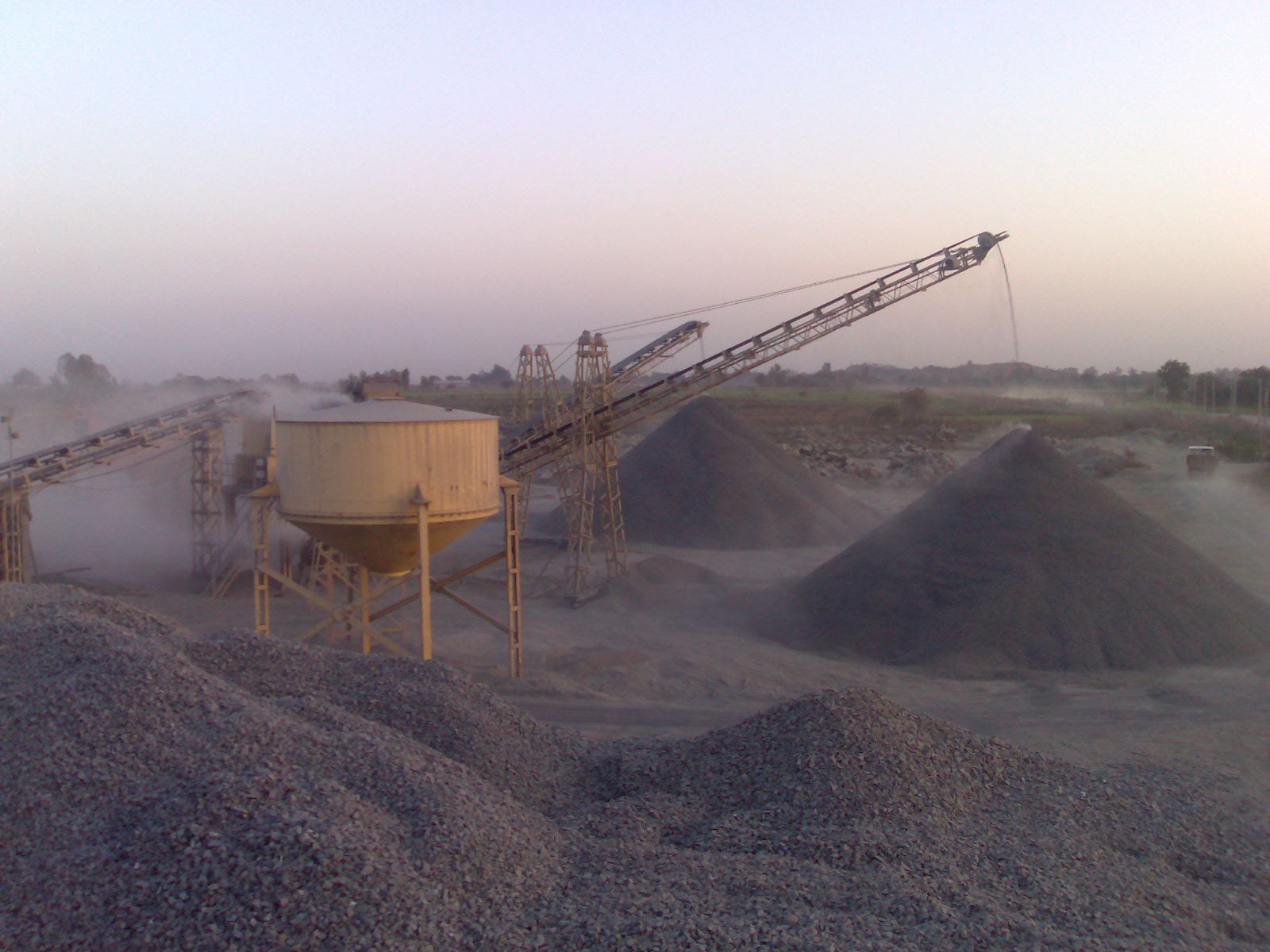 Crusher plant with conveyors and aggregate stockpiles at dusk
