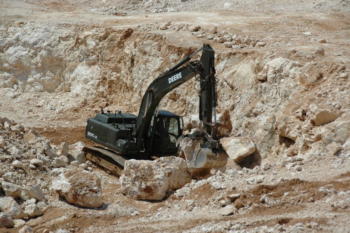 Excavator working among large boulders in a limestone quarry