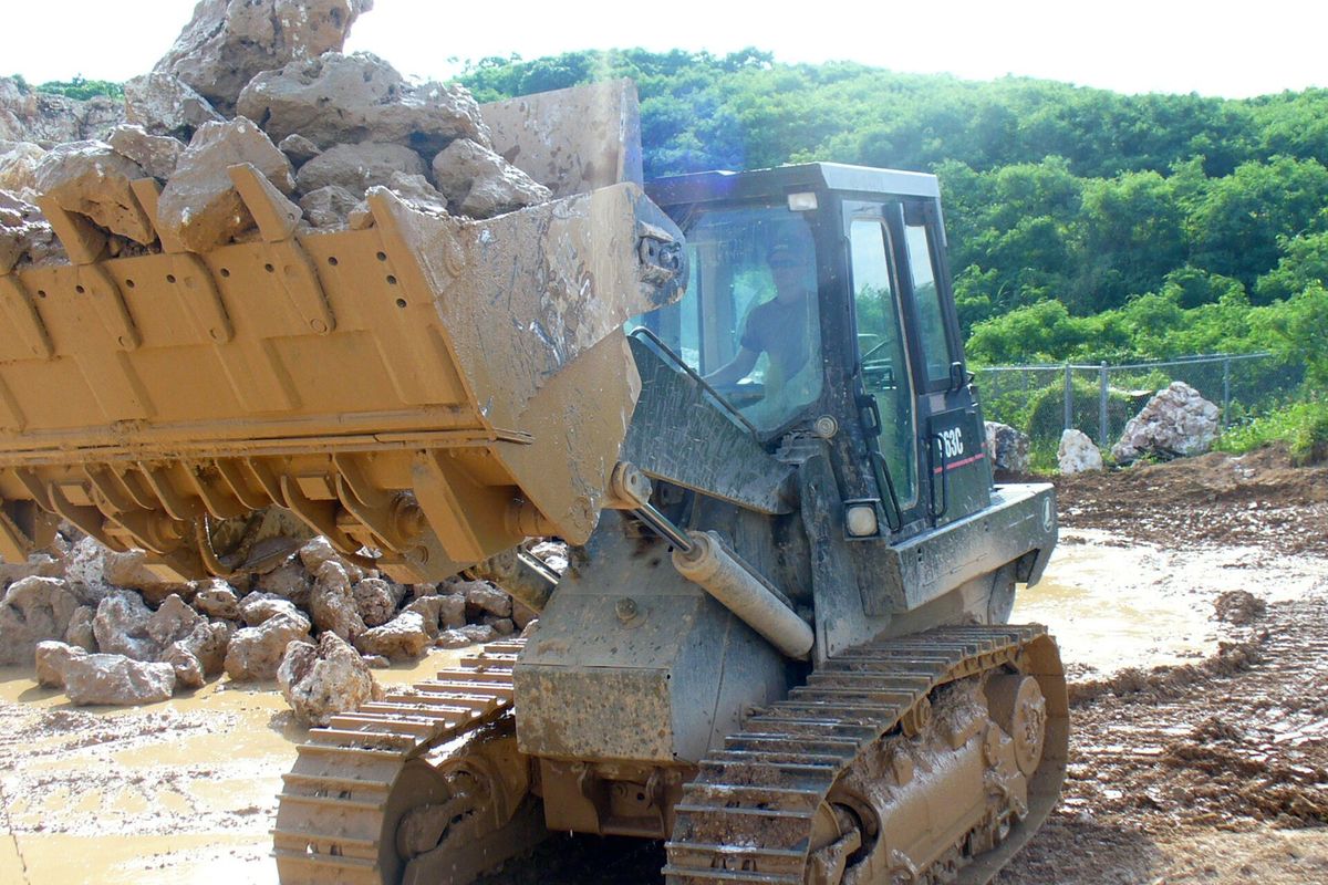 Tracked loader lifting a bucket of blasted rock at a quarry